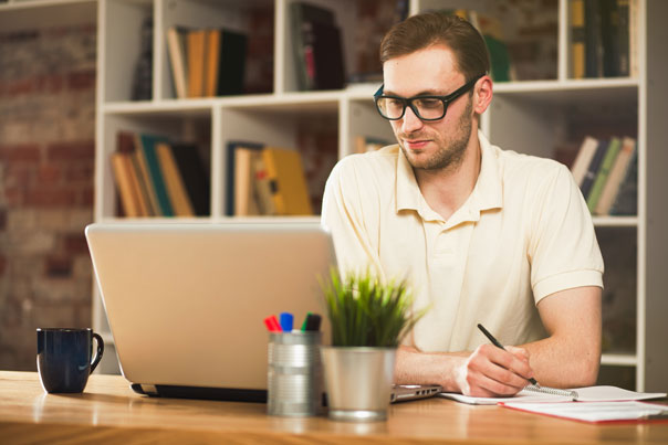 man in white shirt using his laptop