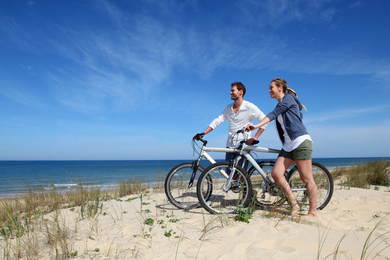 Man and woman with bikes on the beach enjoying a healthy, active recovery