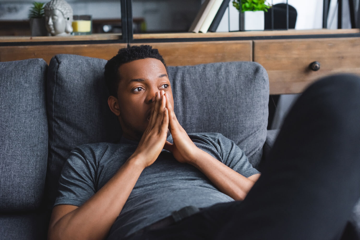 Man laying down on a couch thinking