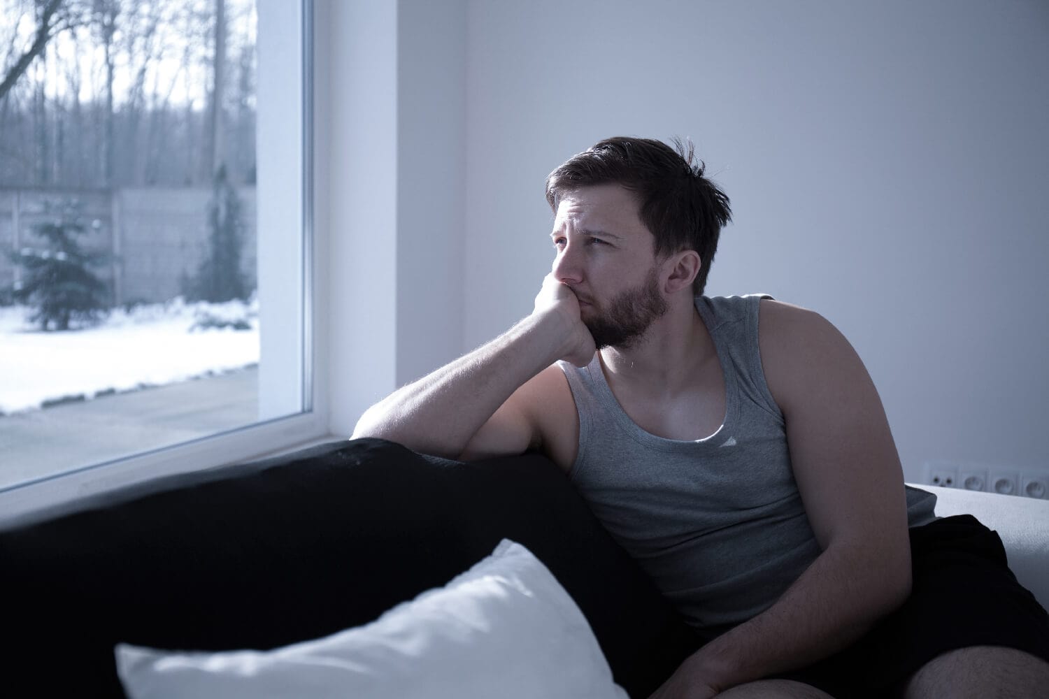 Depressed man sitting on a couch looking outside