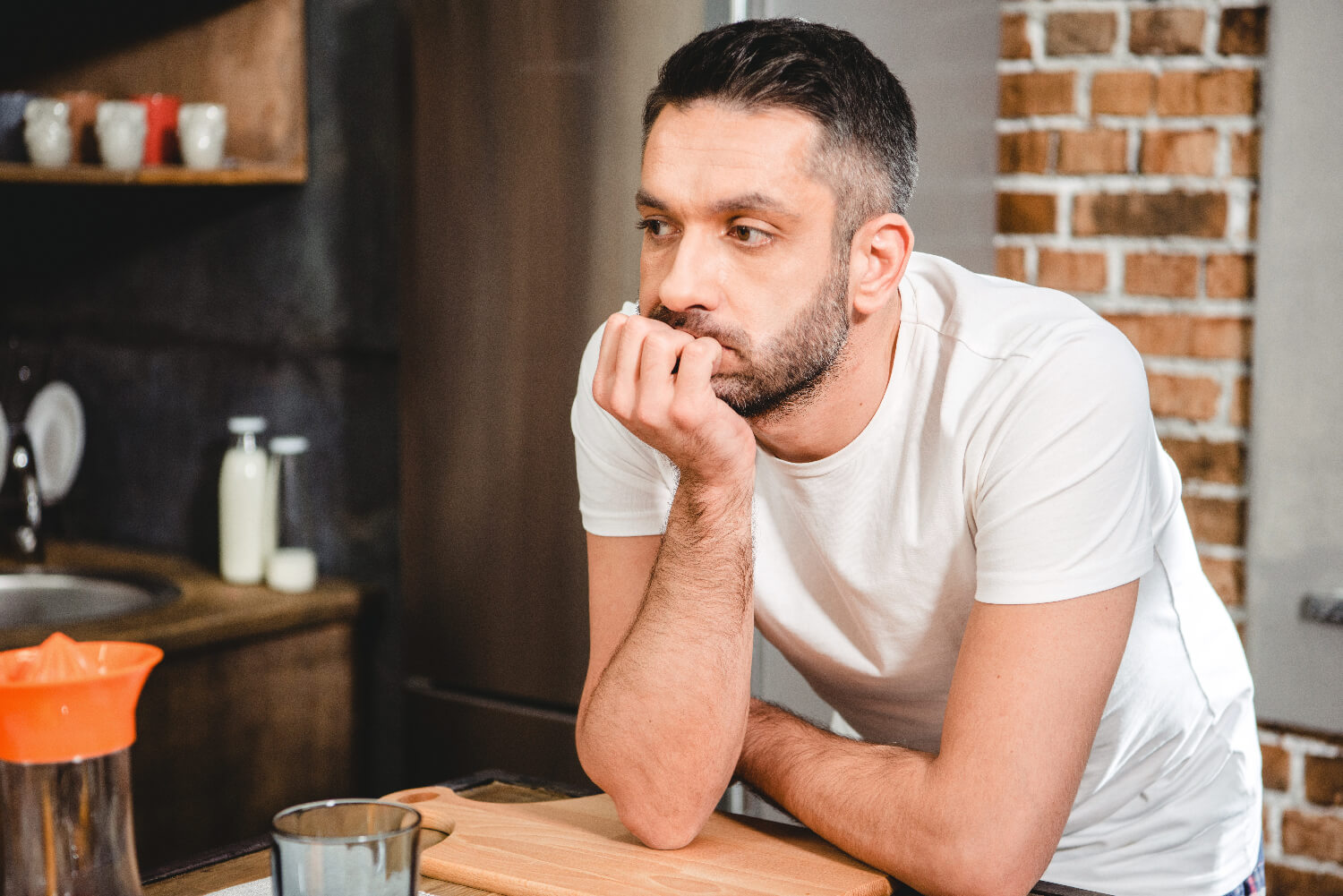 Depressed man leaning on a counter considering alcohol abuse treatment