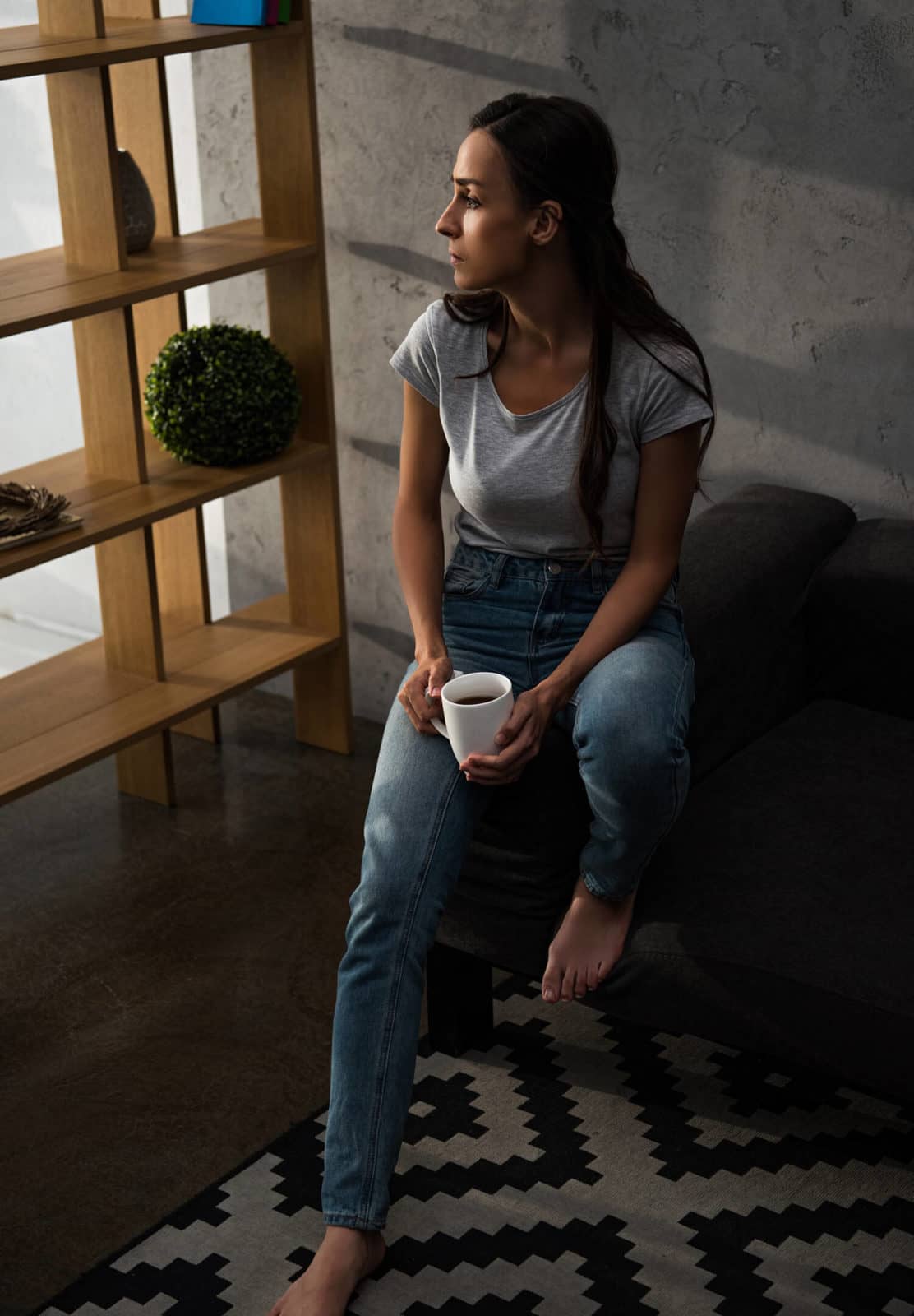 Woman sitting on a couch with coffee detoxing from benzos