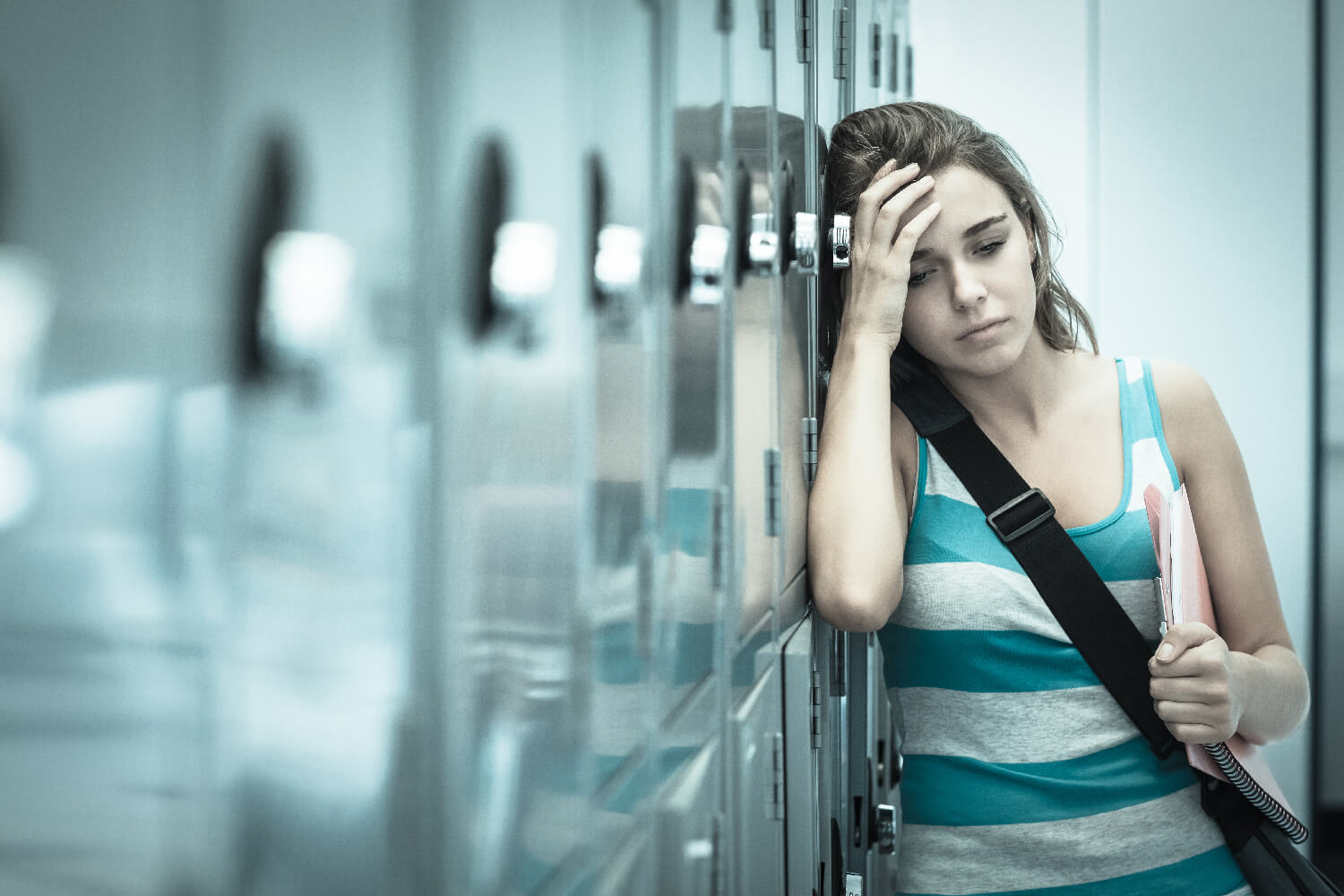 Woman leaning against lockers with her hand on her head