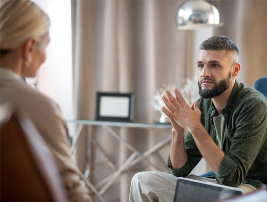 A bearded man in a green shirt engaged in a conversation with a woman